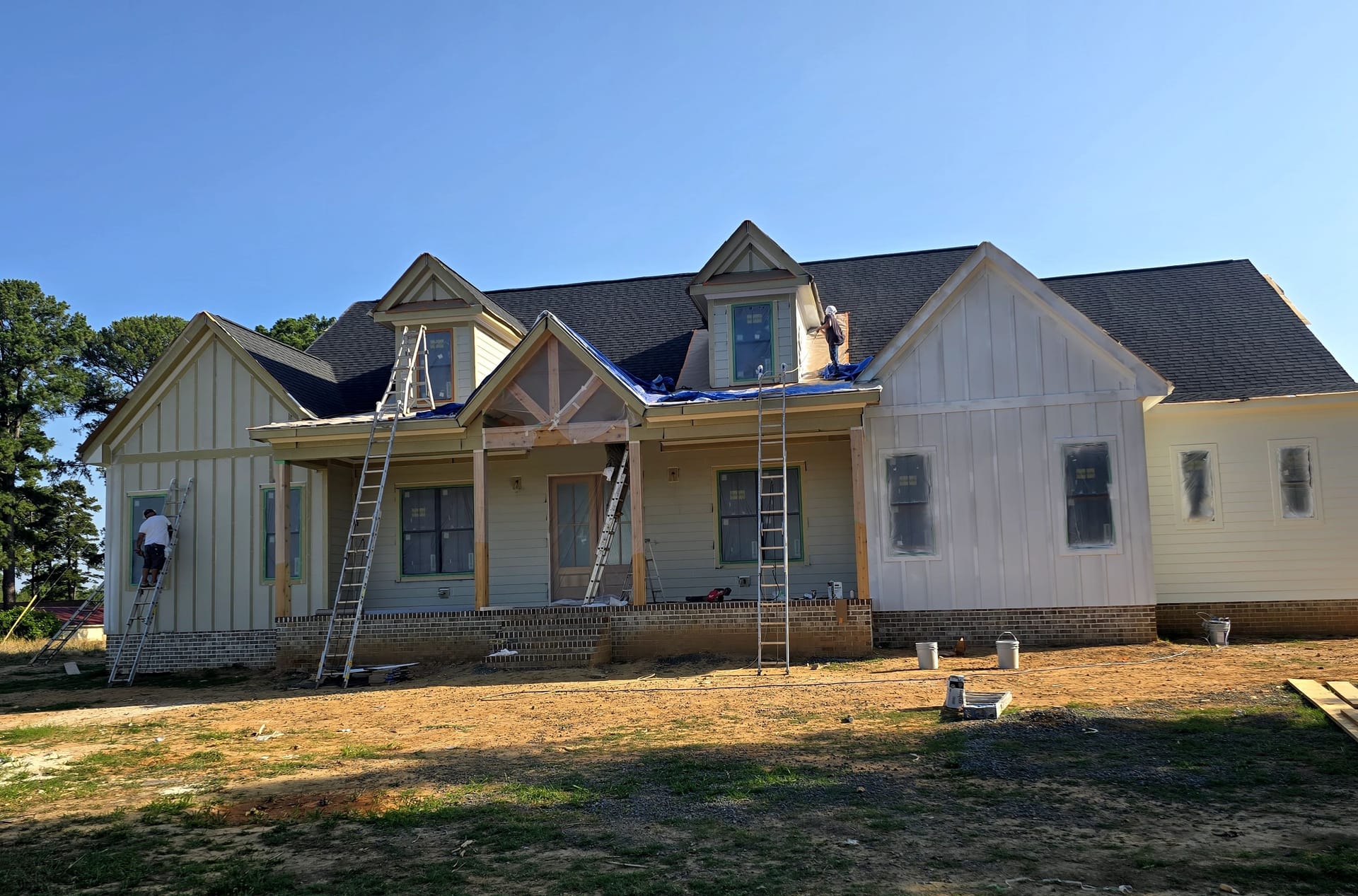 A crew working from ladders on the exterior of a house mid-repaint